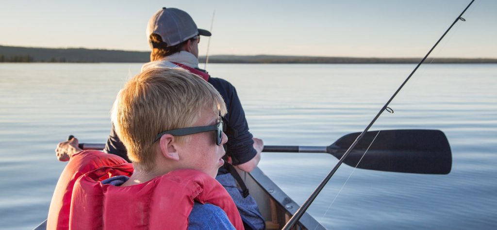 Boy and his dad fishing in a boat