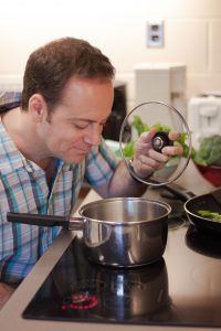 Man looking into pot cooking on the stovetop