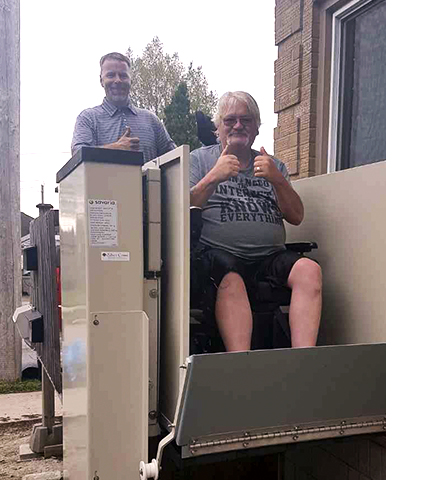 Robert in wheelchair lift with John from Silver Cross 