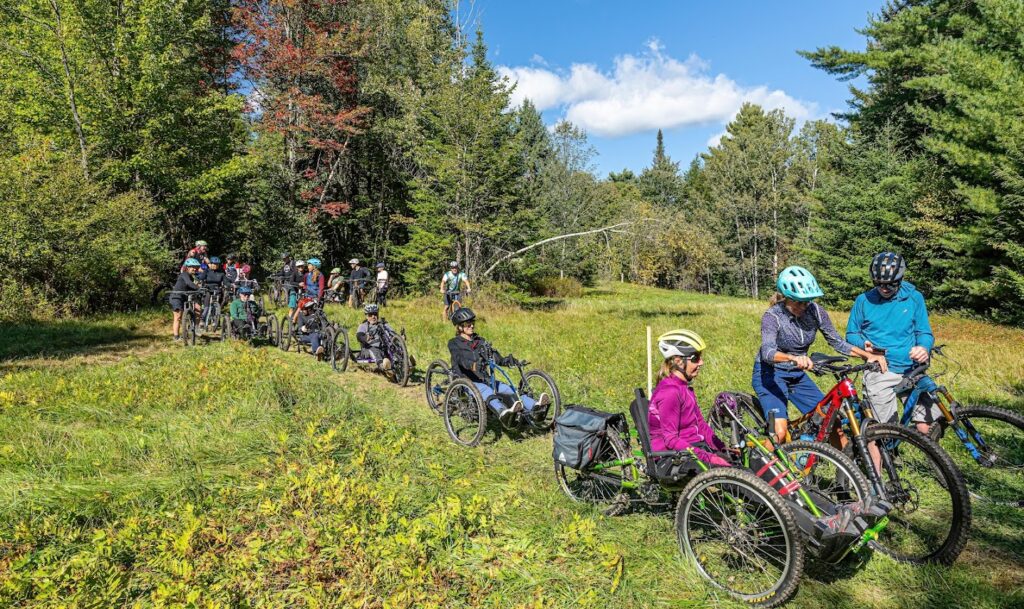 Group of people outdoors in forest, riding adaptive mountain bikes