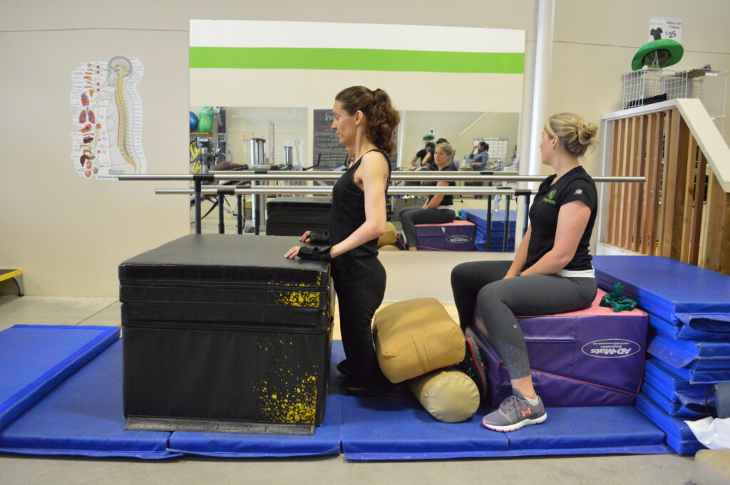 Woman with disability in therapy session on mat with exercise equipment.