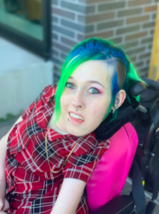 Woman with blue hair and pink shirt using wheelchair