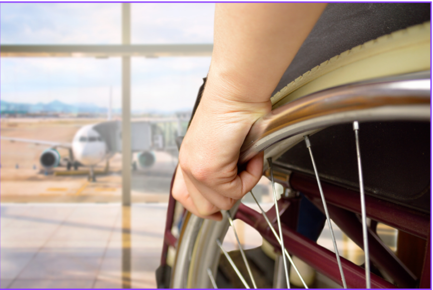 Hand of individual using a wheelchair facing window showing airplane at airport