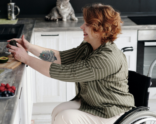A woman in a wheelchair prepares her lunch in an accessible kitchen.