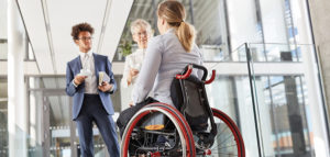 Young woman in a wheelchair discussing work with her colleagues.