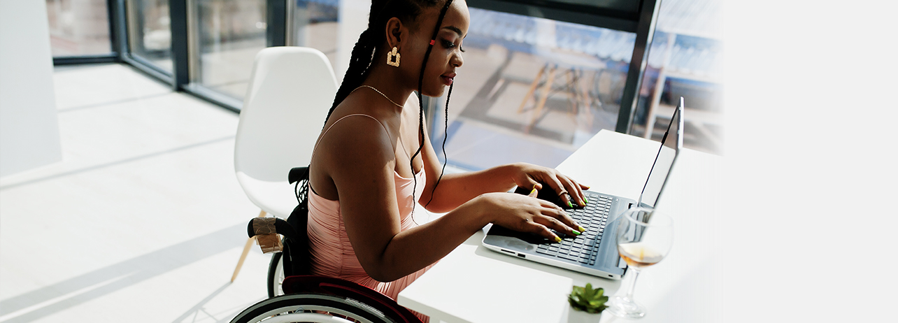 Young women in her wheelchair using her laptop.