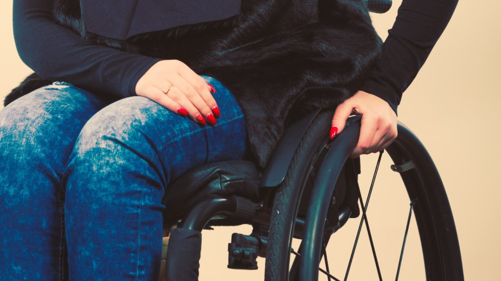 Lady in wheelchair with red nails, jeans and black shirt