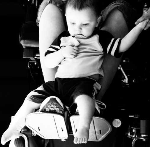 baby held by parent in a wheelchair