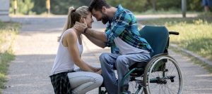 A young couple sharing an intimate moment, the man uses a wheelchair.