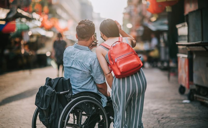 Two friends, one in a wheelchair, the other standing, being toursits